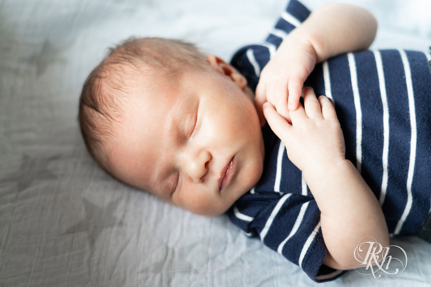 Baby dressed in stripped shirt sleeps during newborn photography session in Ham Lake, Minnesota.