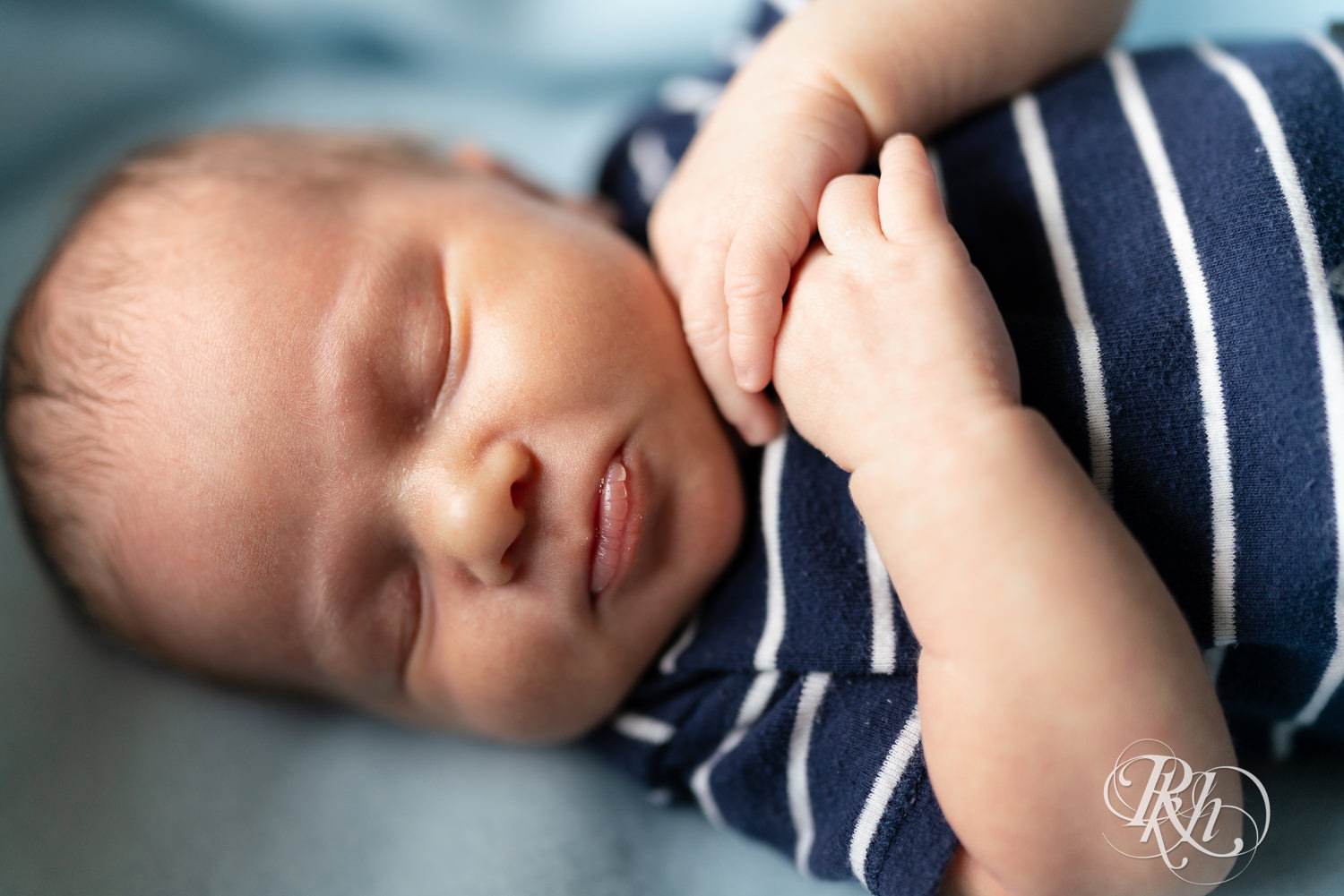 Baby dressed in stripped shirt sleeps during newborn photography session in Ham Lake, Minnesota.