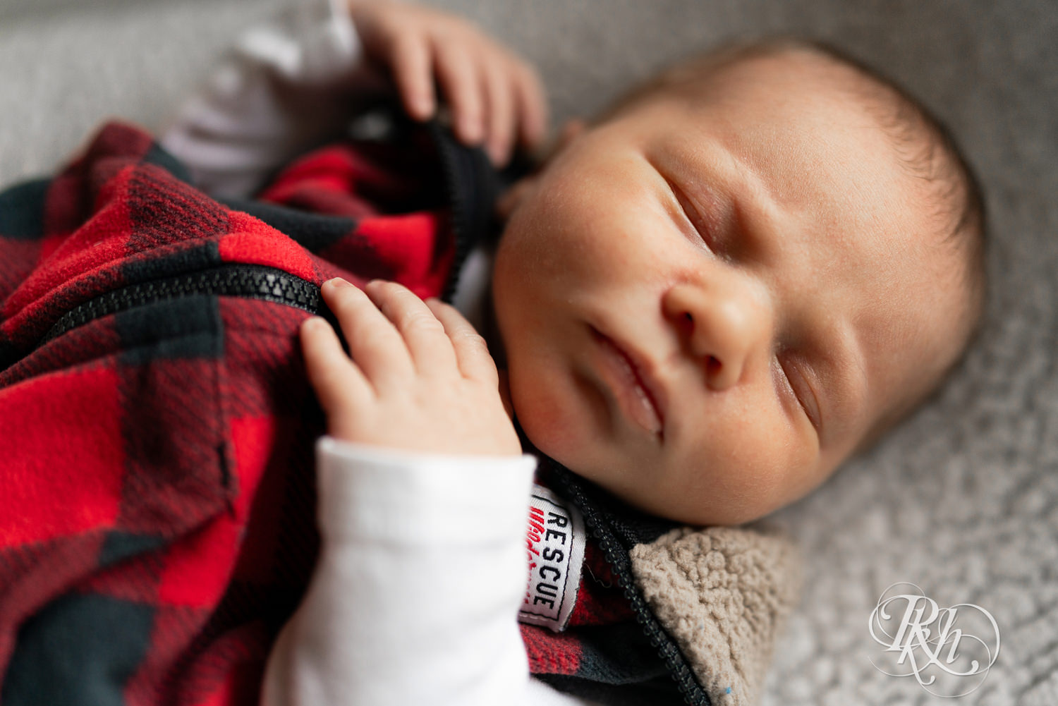 Baby dressed in flannel sleeps during newborn photography session in Ham Lake, Minnesota.