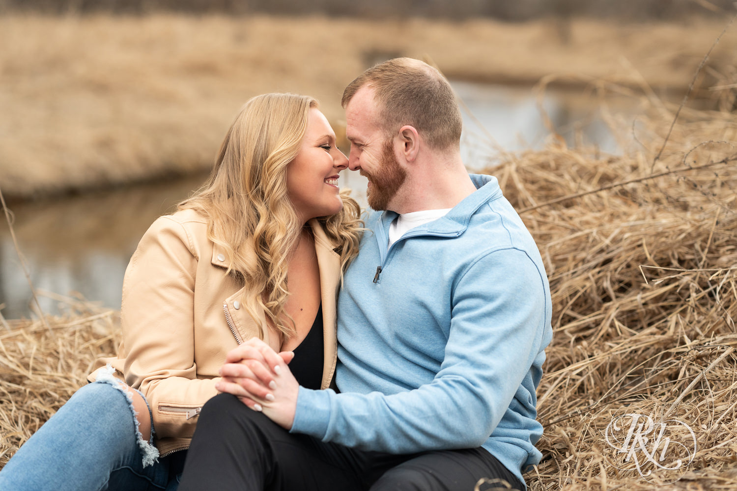 Man in blue shirt and woman in jeans smile during engagement photography at Rice Creek Regional Trail in Shoreview, Minnesota.