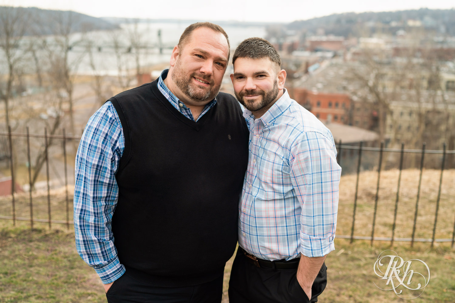 Two men in plaid shirts smile at each other during engagement photography in Stillwater, Minnesota.