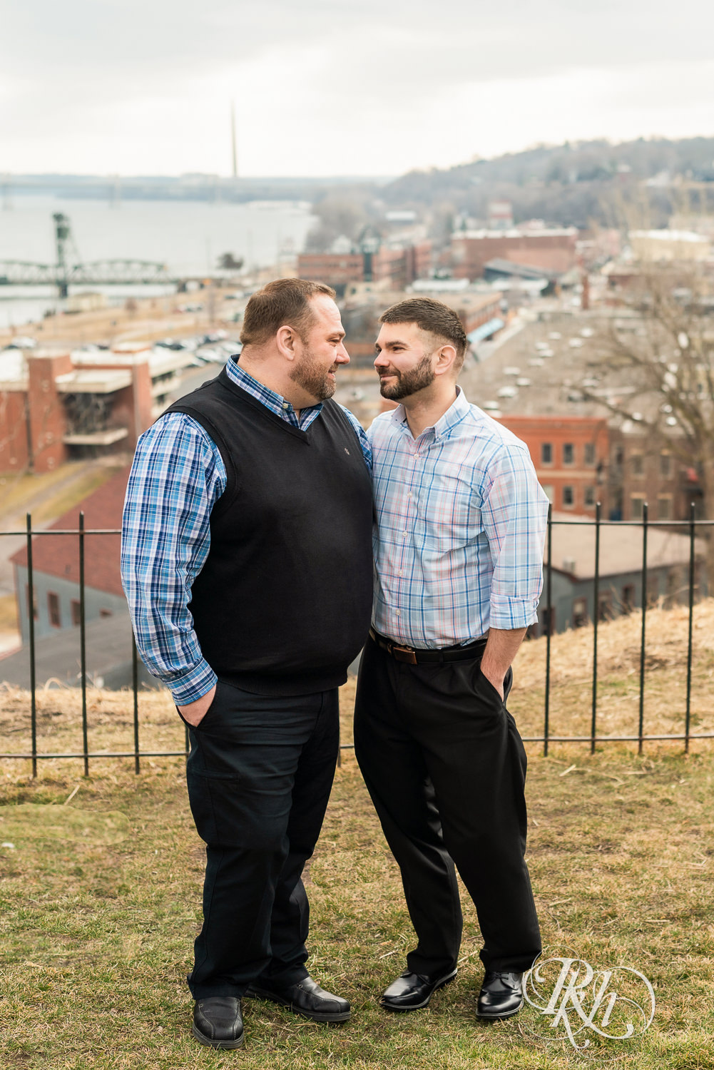 Two men in plaid shirts smile at each other during engagement photography in Stillwater, Minnesota.