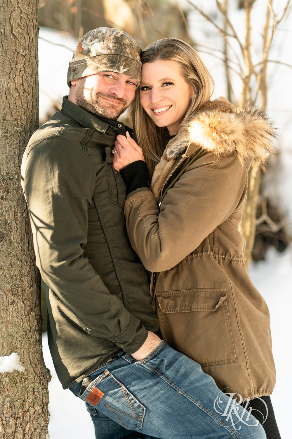 Man in jeans and woman in black dress smile at sunrise during Taylor's Falls engagement photography session.