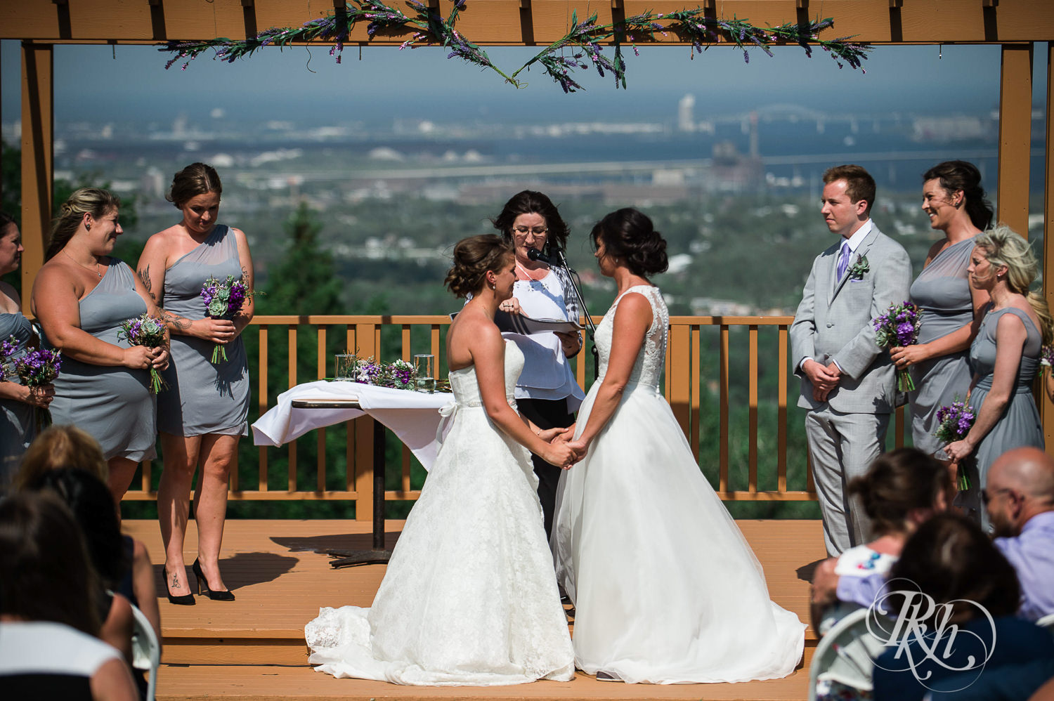 Lesbian brides hold hands during outdoor ceremony at Spirit Mountain in Duluth, Minnesota.