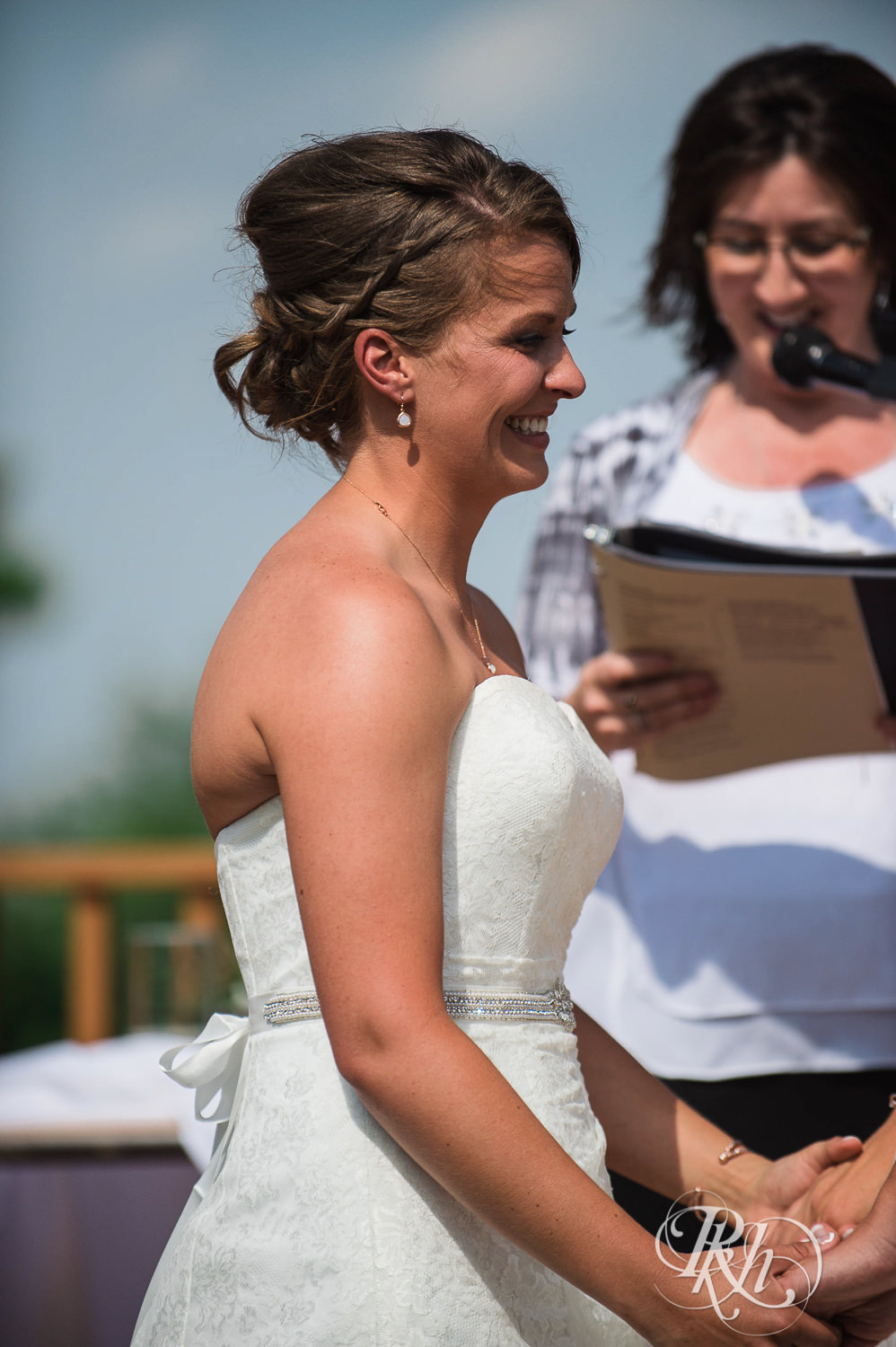 Lesbian brides smile during outdoor ceremony at Spirit Mountain in Duluth, Minnesota.