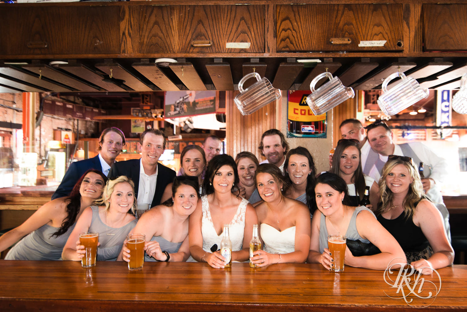 Lesbian brides smiles with wedding party in a bar in Duluth, Minnesota.