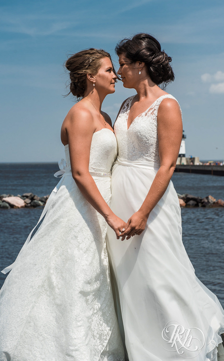 Lesbian brides smile on the shore of Lake Superior in Duluth, Minnesota.