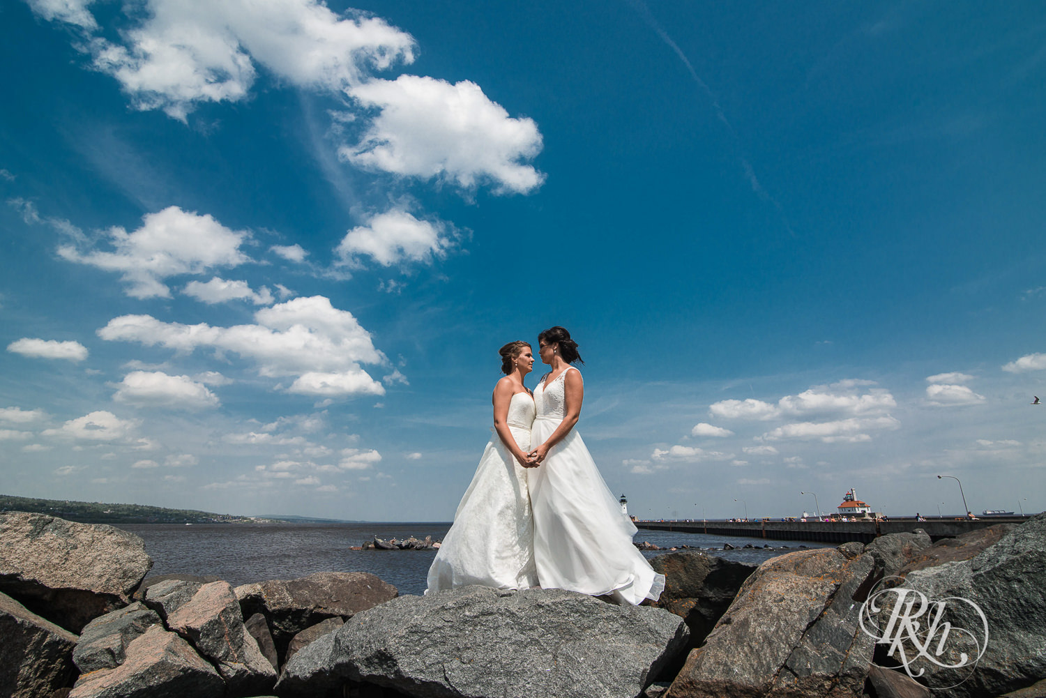 Lesbian brides smile on the shore of Lake Superior in Duluth, Minnesota.