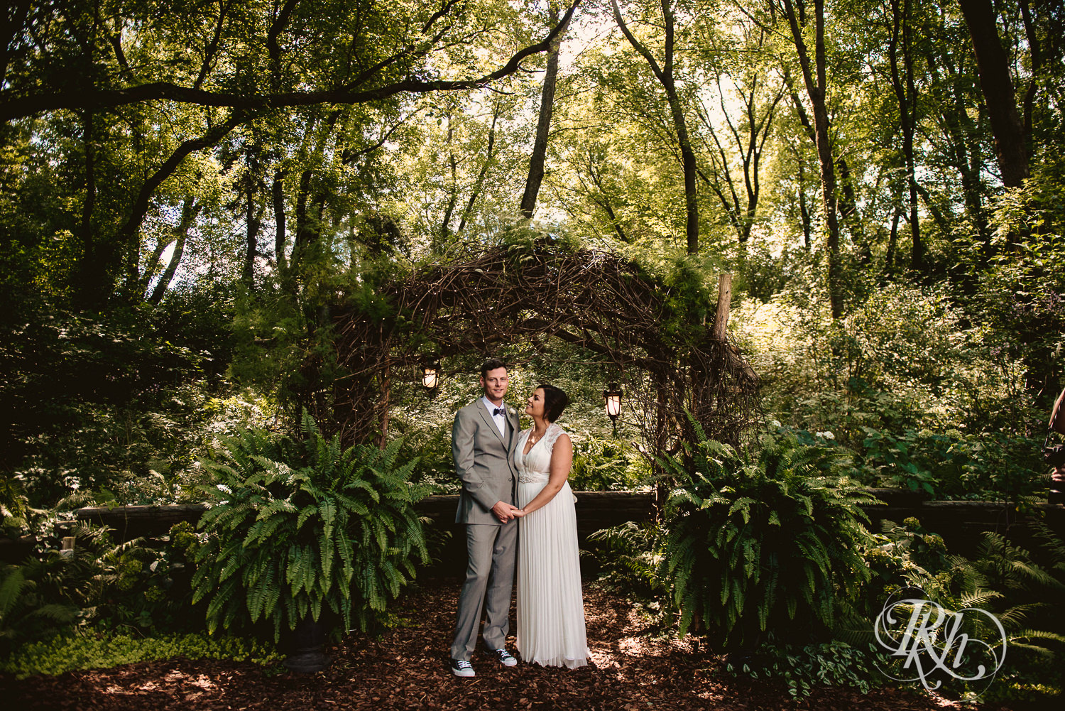 Bride and groom smile under arch at Camrose Hill Flower Farm in Stillwater, Minnesota.