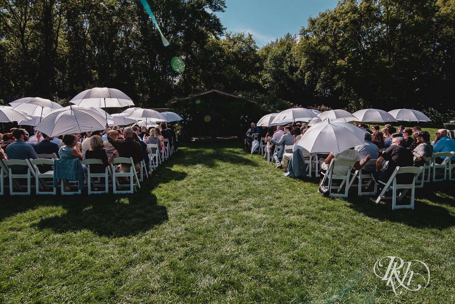 Guests smile under umbrellas before wedding ceremony at Camrose Hill Flower Farm in Stillwater, Minnesota.
