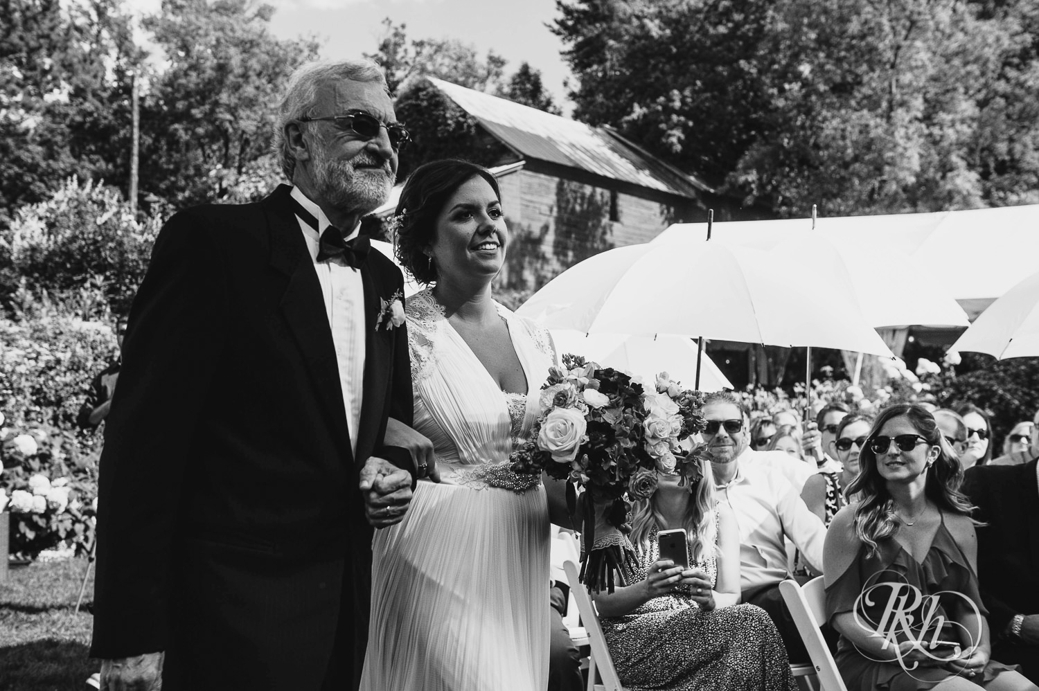Bride and dad walk down the aisle during wedding ceremony at Camrose Hill Flower Farm in Stillwater, Minnesota.