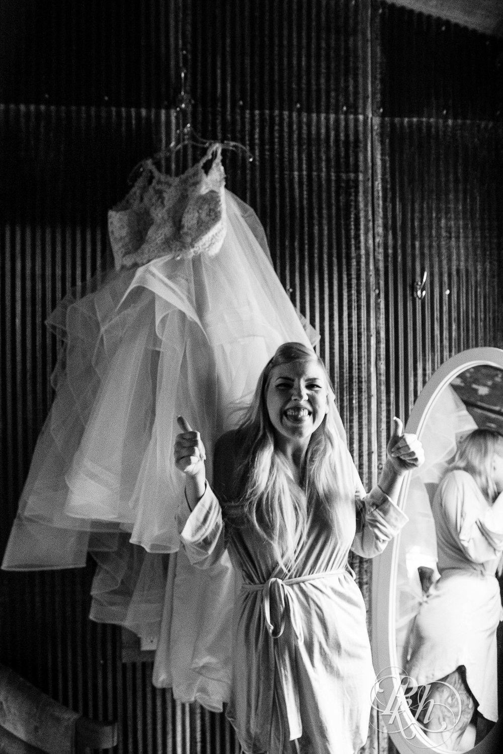 Bride smiles in front of wedding dress at Coops Event Barn in Dodge Center, Minnesota.