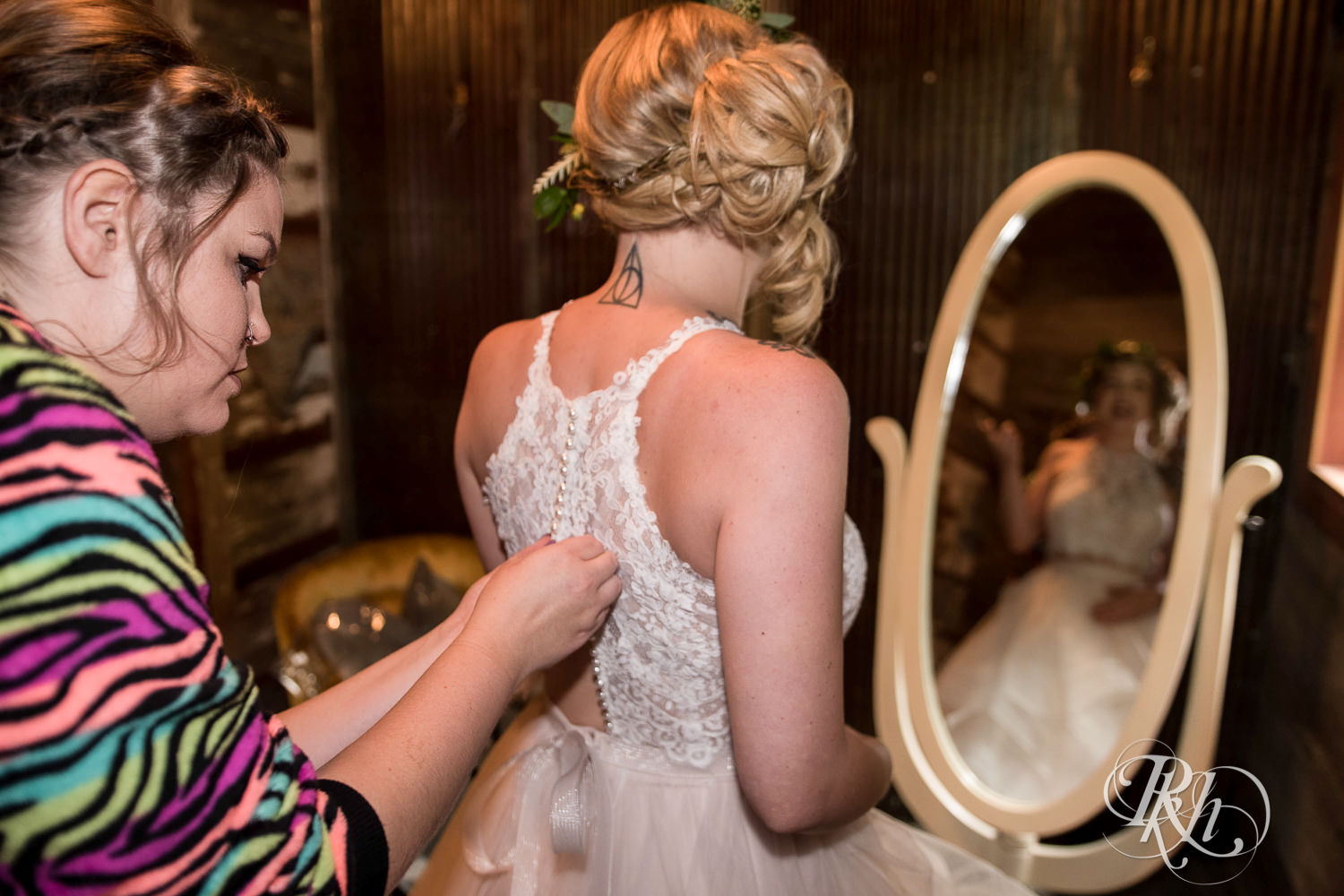 Wedding party helps bride get into wedding dress at Coops Event Barn in Dodge Center, Minnesota.