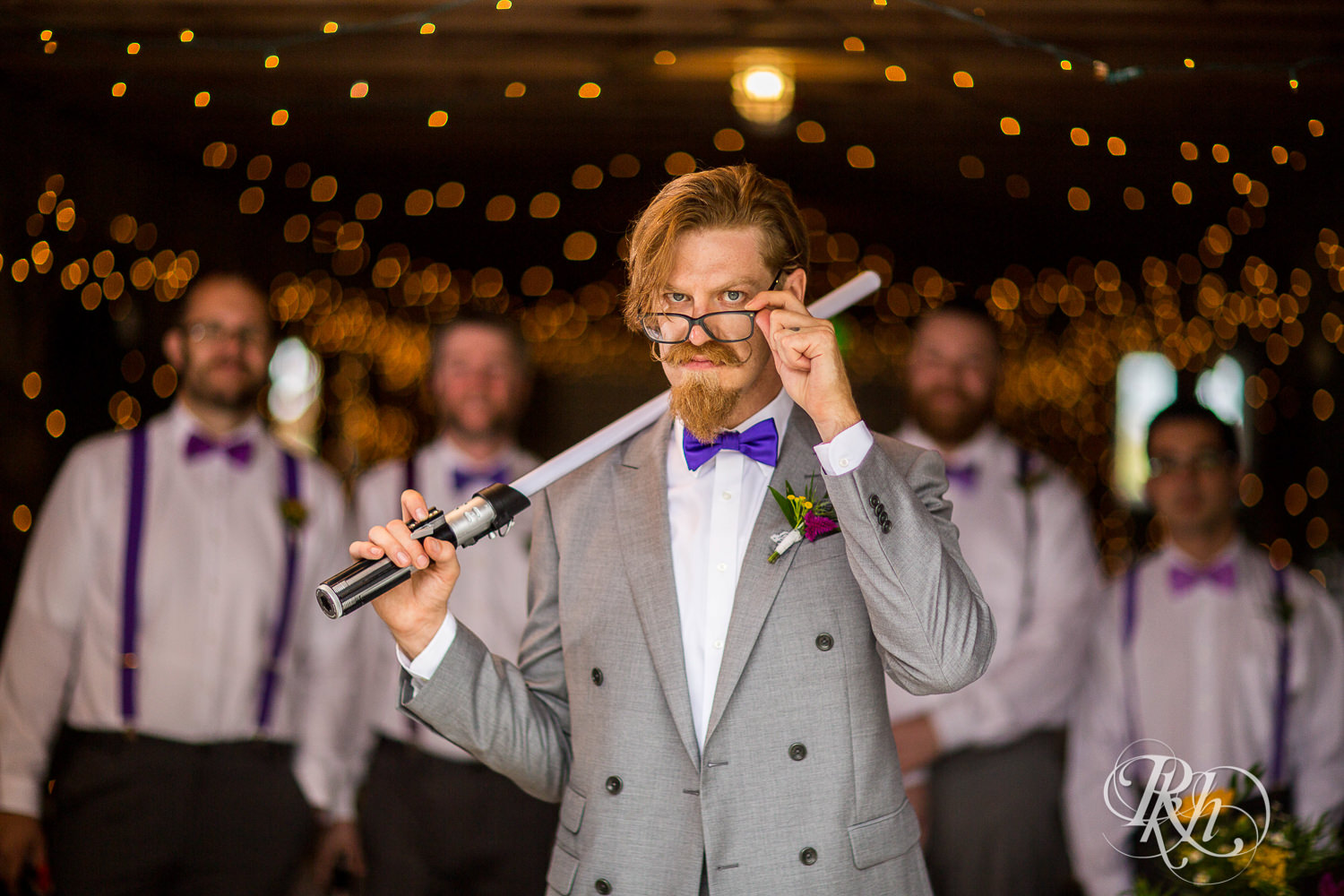 Groom smiles with Star Wars light sabers before wedding at Coops Event Barn in Dodge Center, Minnesota.