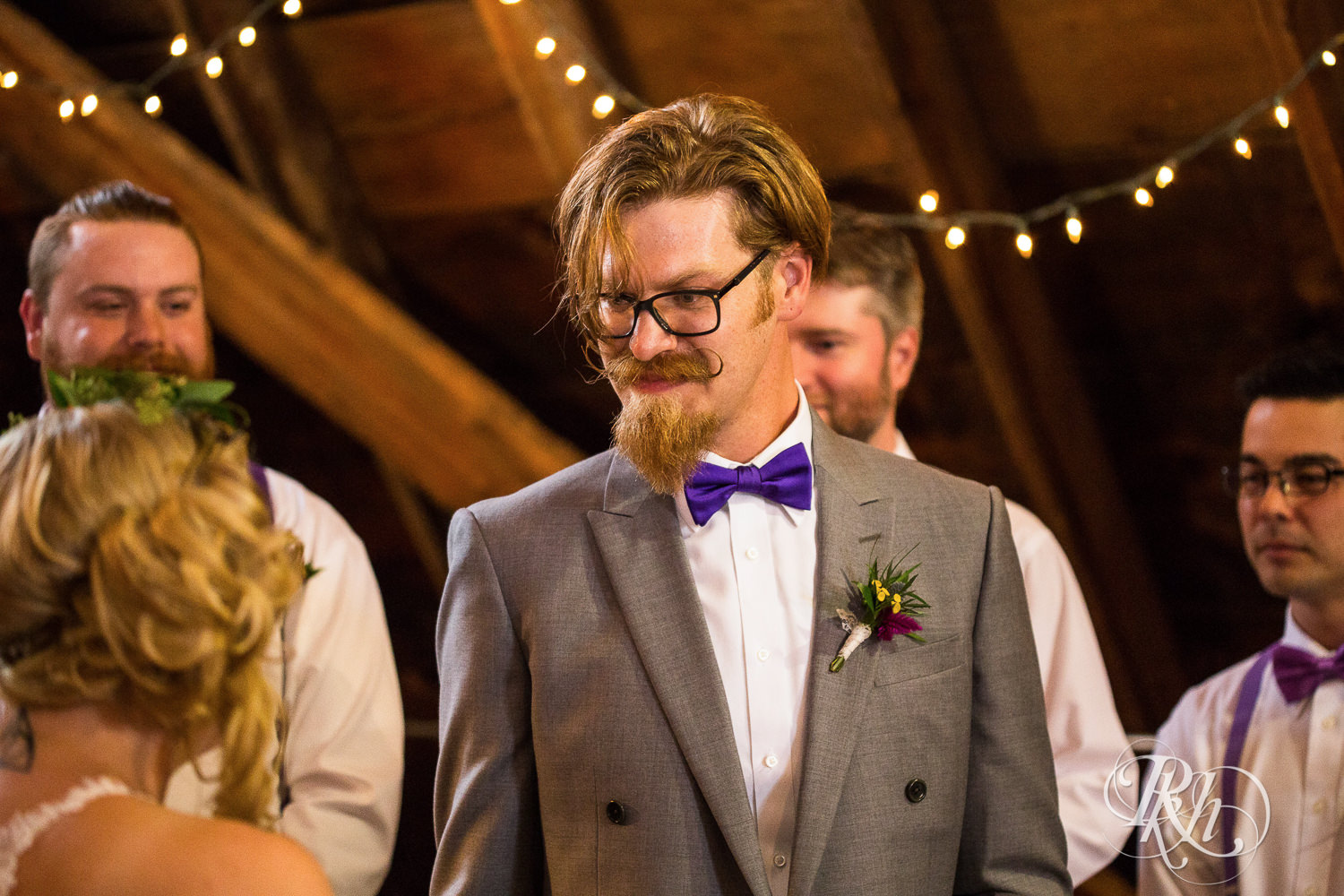 Bride and groom smile during wedding ceremony at Coops Event Barn in Dodge Center, Minnesota.