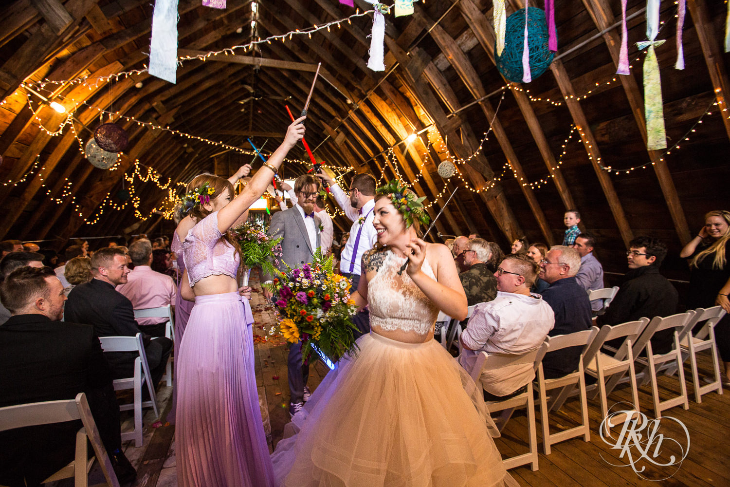Bride and groom walk under lightsabers after wedding ceremony at Coops Event Barn in Dodge Center, Minnesota.