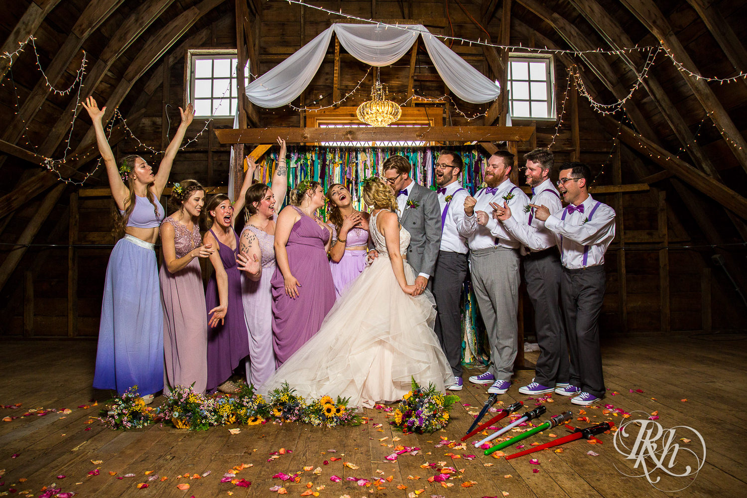 Wedding party smiles with bride and groom at Coops Event Barn in Dodge Center, Minnesota.