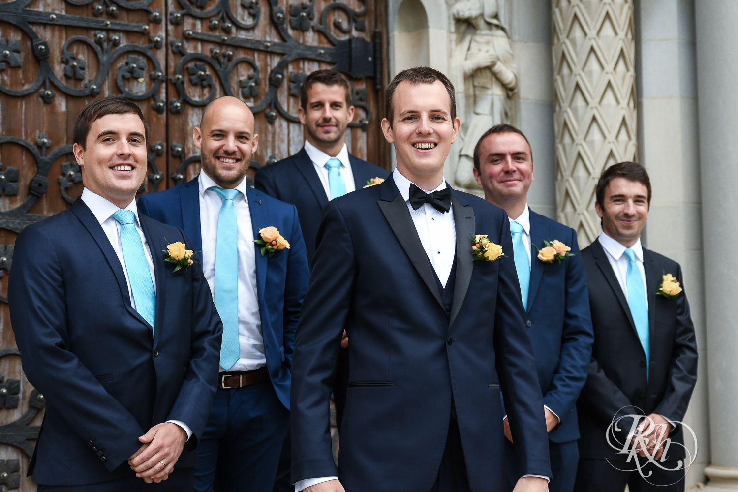 Wedding party smiles on the steps of St. Thomas Moore Catholic Church in Saint Paul, Minnesota.
