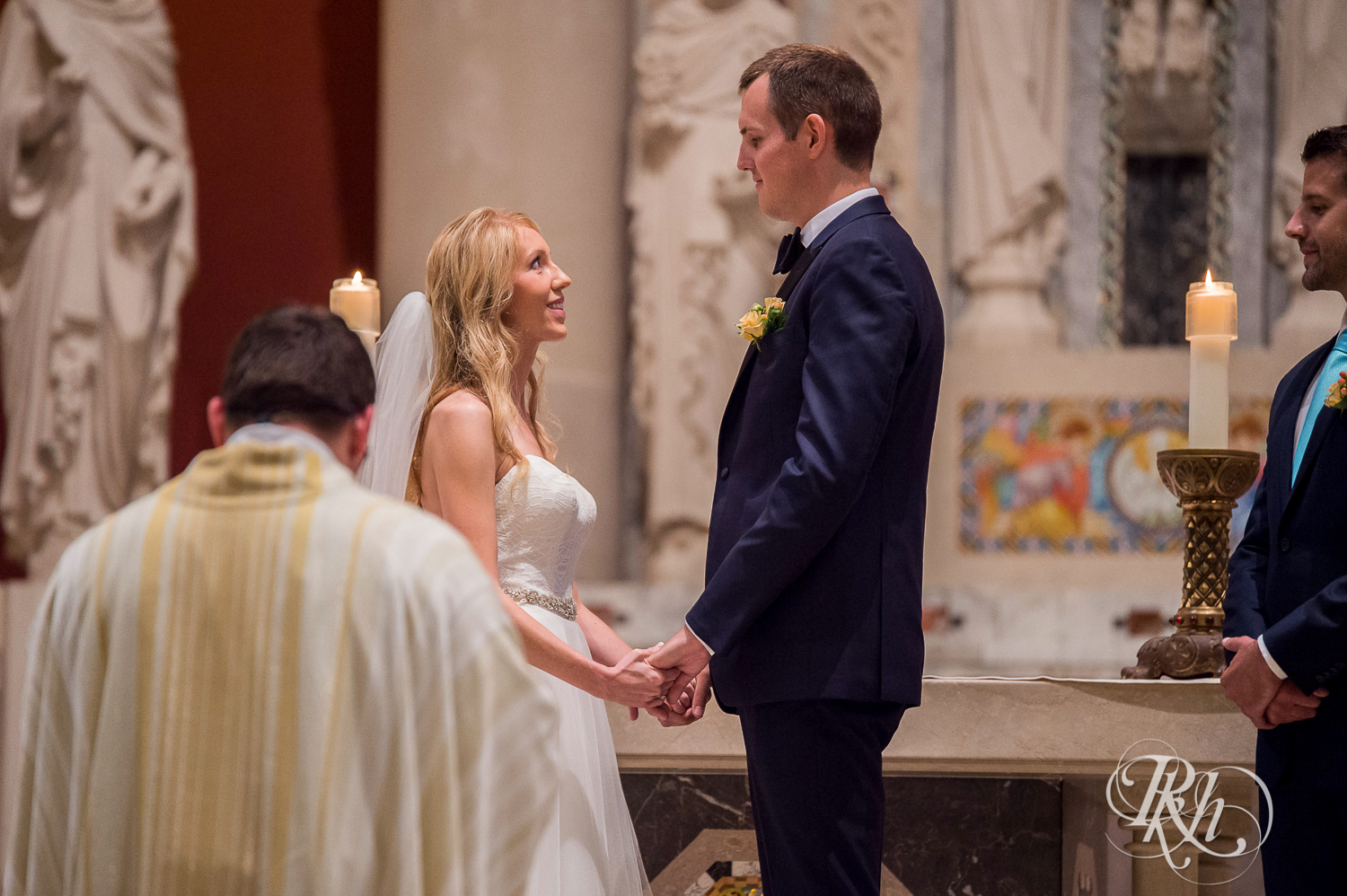 Bride and groom smile during wedding ceremony at St. Thomas Moore Catholic Church in Saint Paul, Minnesota.
