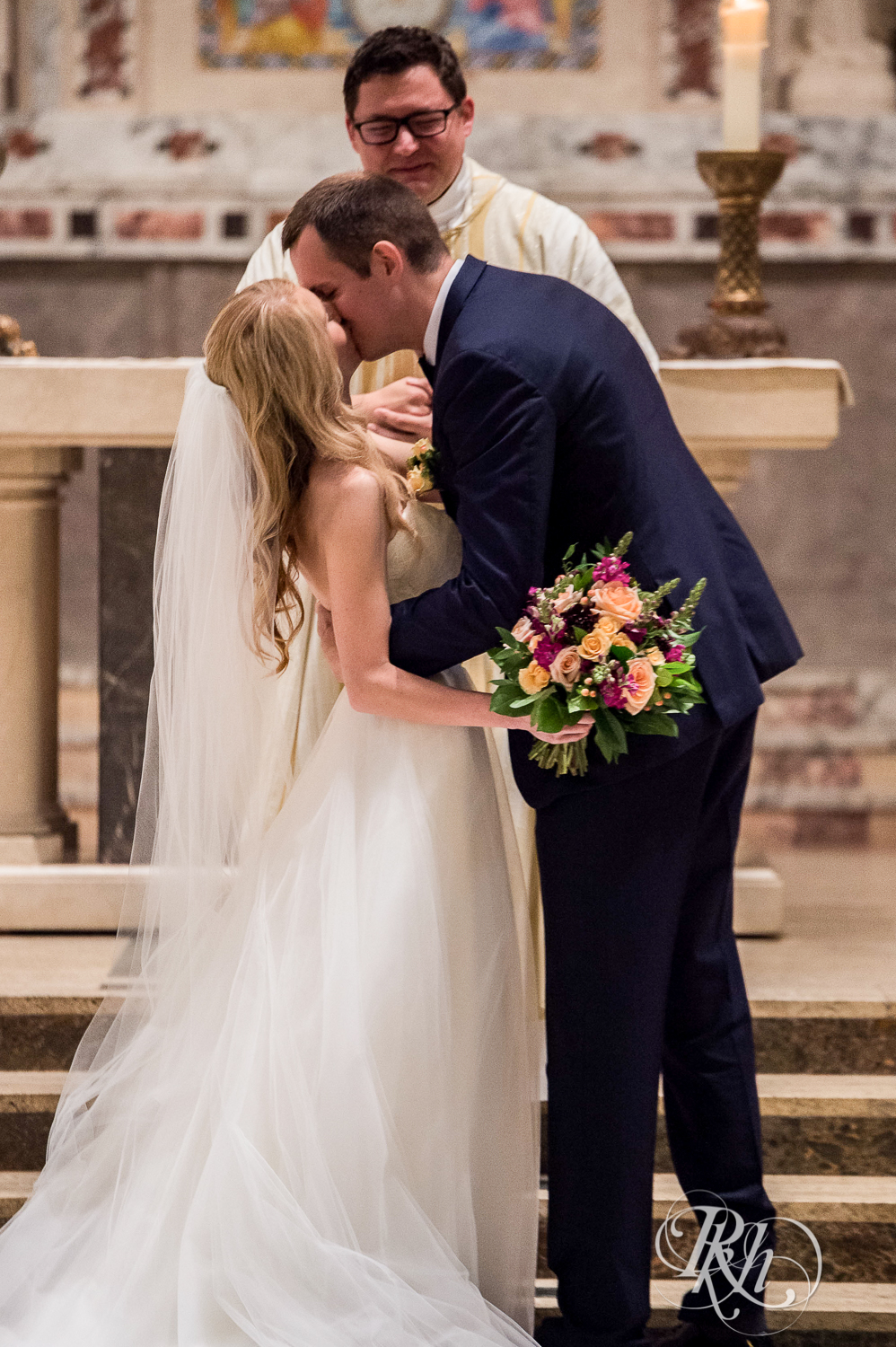 Bride and groom kiss during wedding ceremony at St. Thomas Moore Catholic Church in Saint Paul, Minnesota.