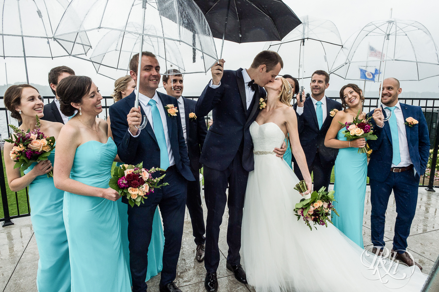 Bride and groom kiss with umbrella on rainy wedding day at White Bear Yacht Club in Dellwood, Minnesota.