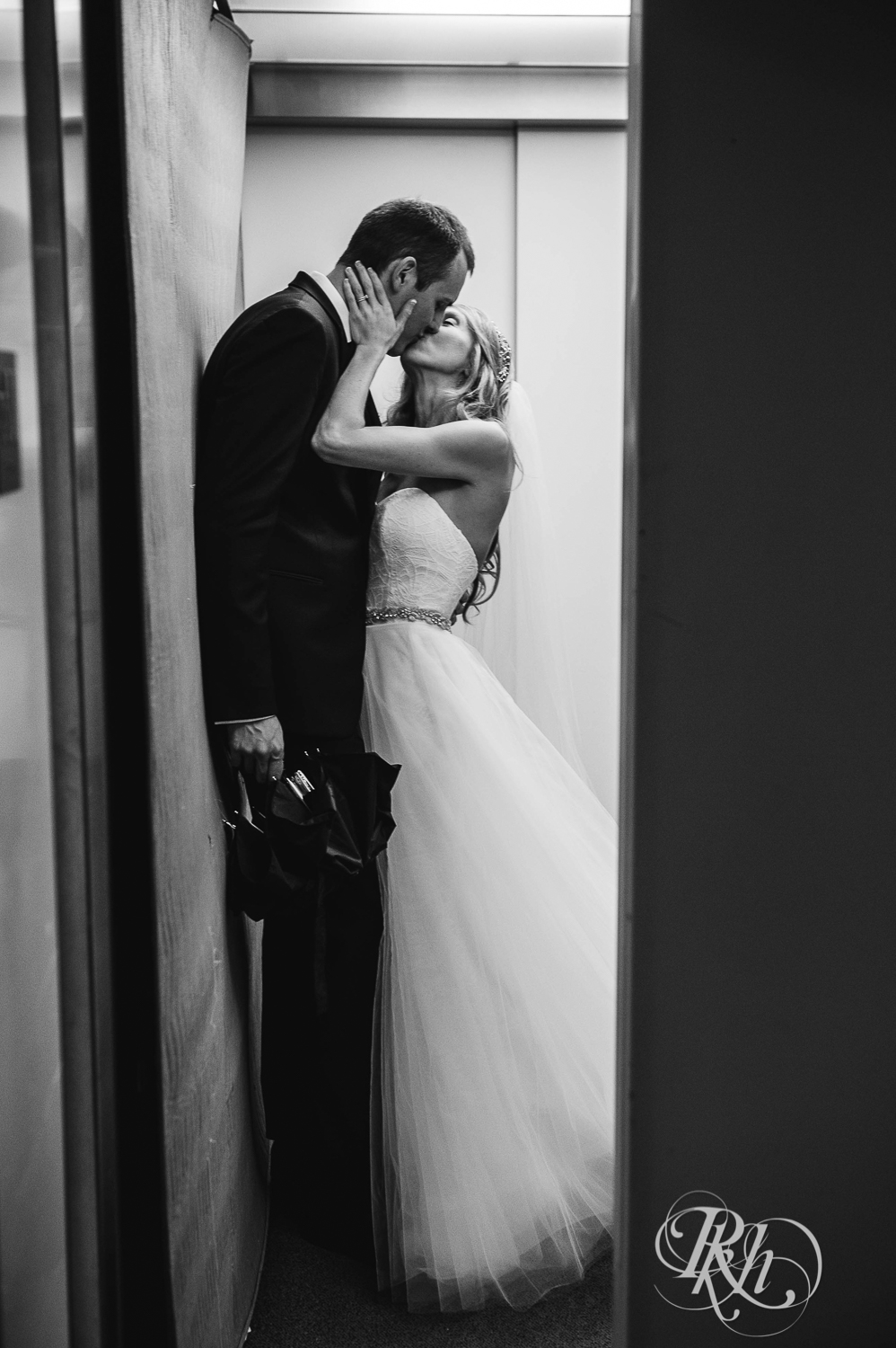 Bride and groom kiss in elevator after wedding at White Bear Yacht Club in Dellwood, Minnesota.