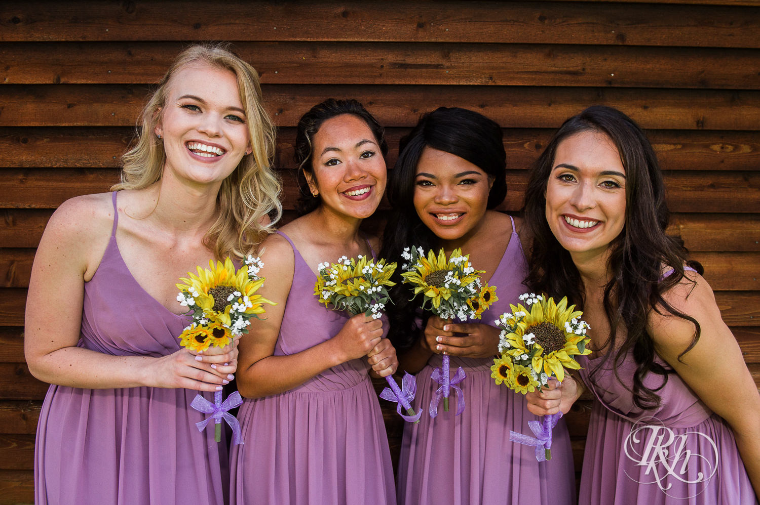 Wedding party smiles holding sunflowers during barn wedding at Birch Hill Barn in Glenwood City, Wisconsin.