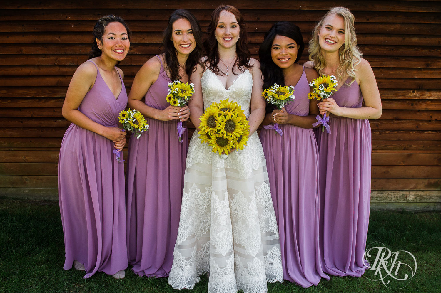 Wedding party smiles holding sunflowers during barn wedding at Birch Hill Barn in Glenwood City, Wisconsin.