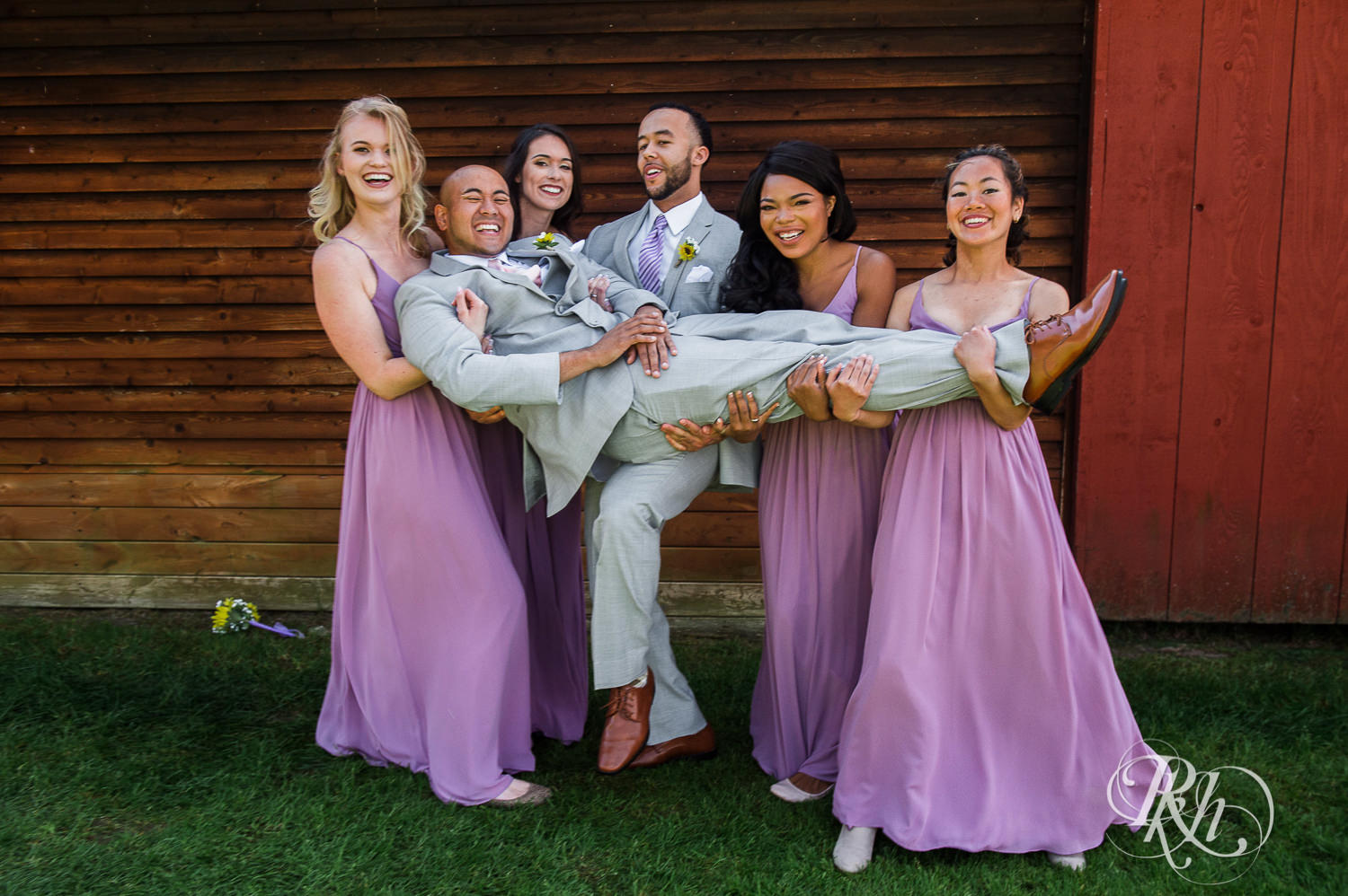 Wedding party smiles holding groom during barn wedding at Birch Hill Barn in Glenwood City, Wisconsin.