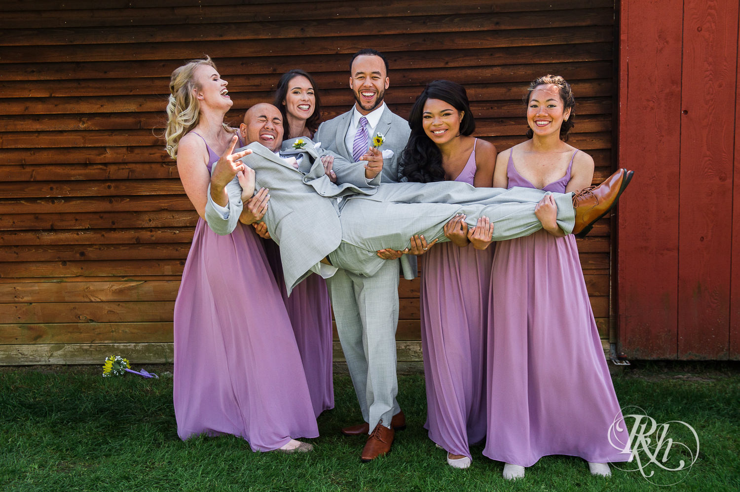 Wedding party smiles holding groom during barn wedding at Birch Hill Barn in Glenwood City, Wisconsin.