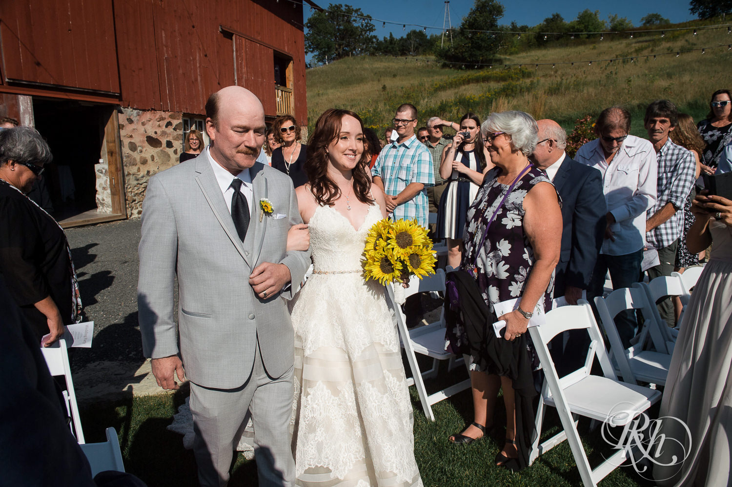 Bride and dad walk down the aisle during barn wedding ceremony at Birch Hill Barn in Glenwood City, Wisconsin.