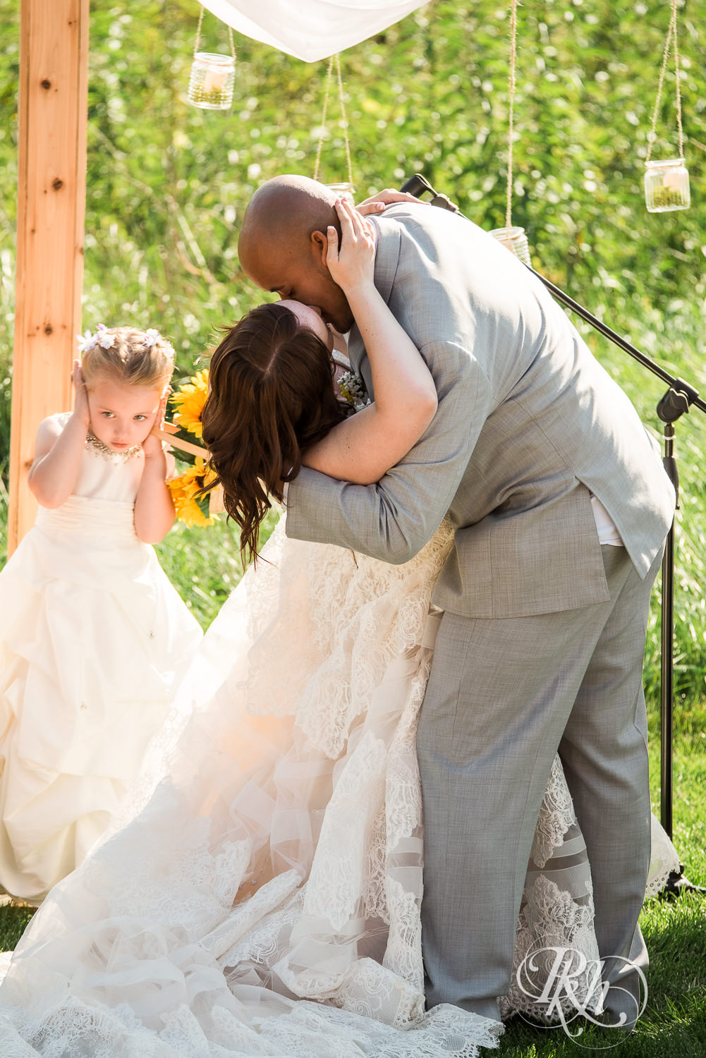 Bride and Asian groom kiss during barn wedding ceremony at Birch Hill Barn in Glenwood City, Wisconsin.