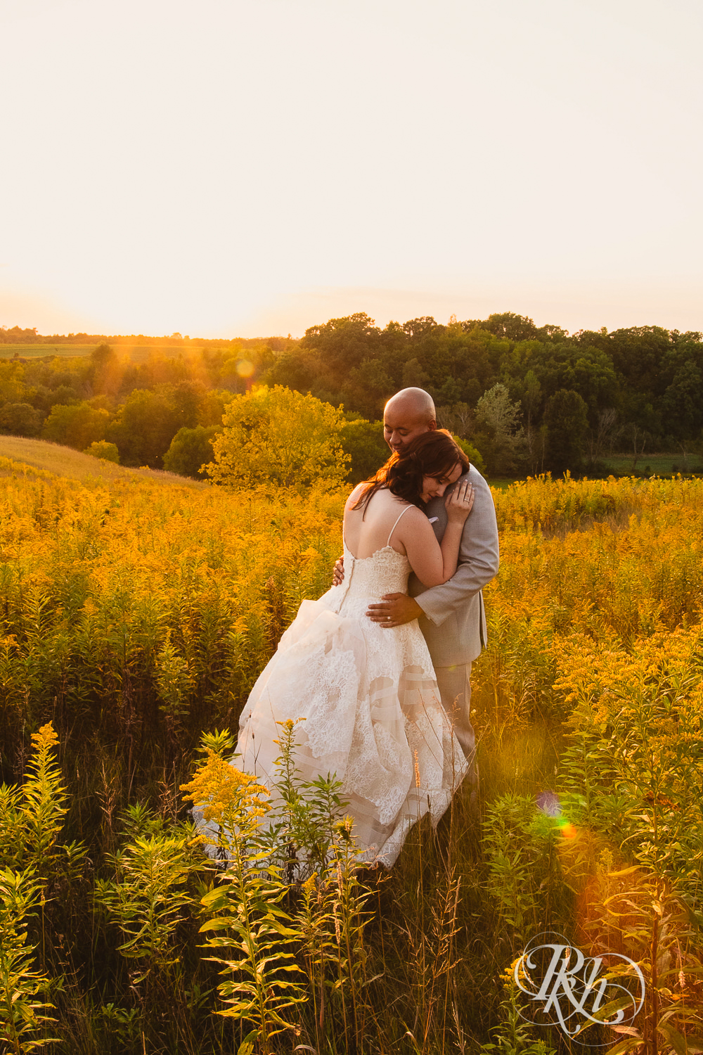 Bride and Asian groom smile during sunset in field on a hill at Birch Hill Barn in Glenwood City, Wisconsin.