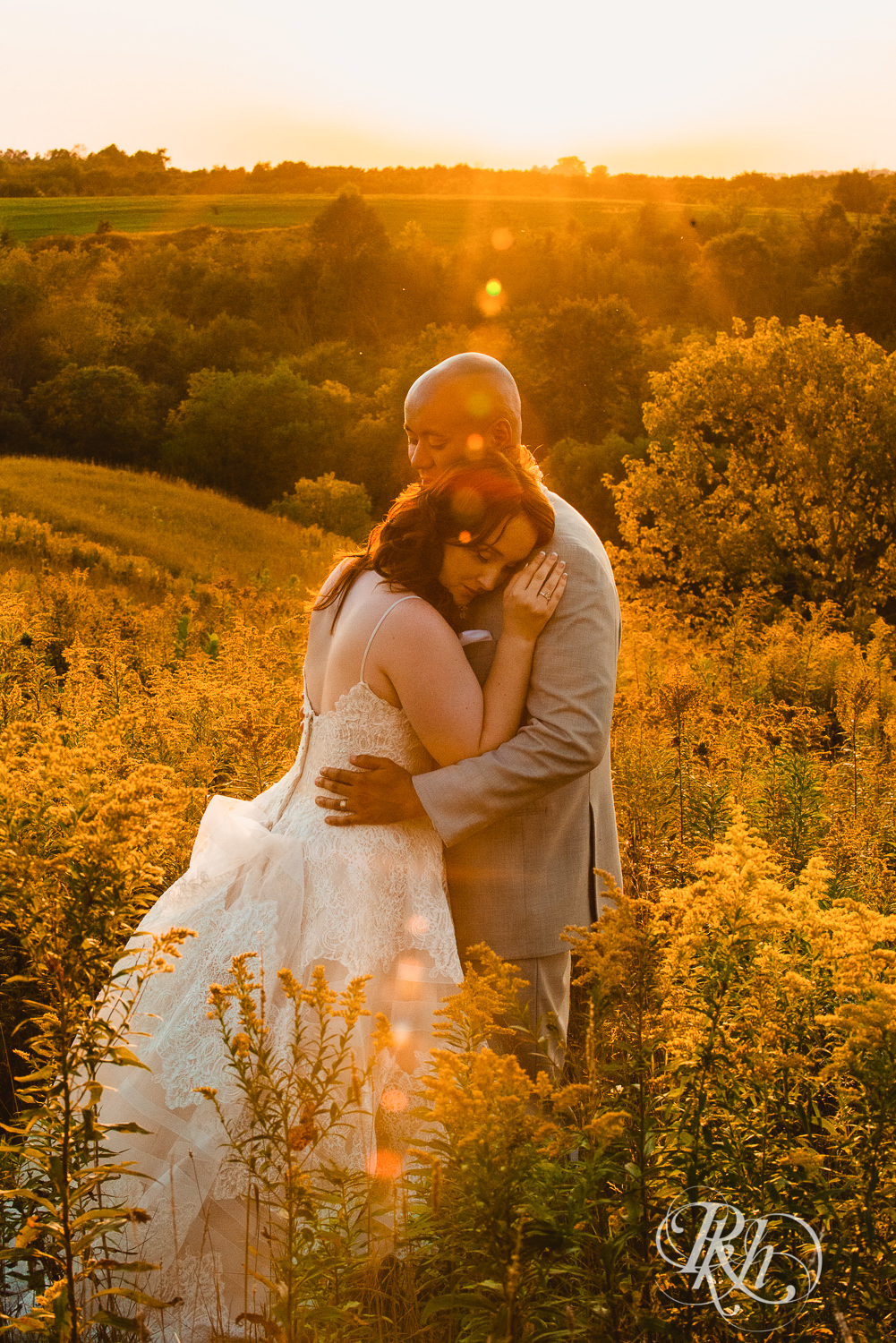 Bride and Asian groom smile during sunset in field on a hill at Birch Hill Barn in Glenwood City, Wisconsin.