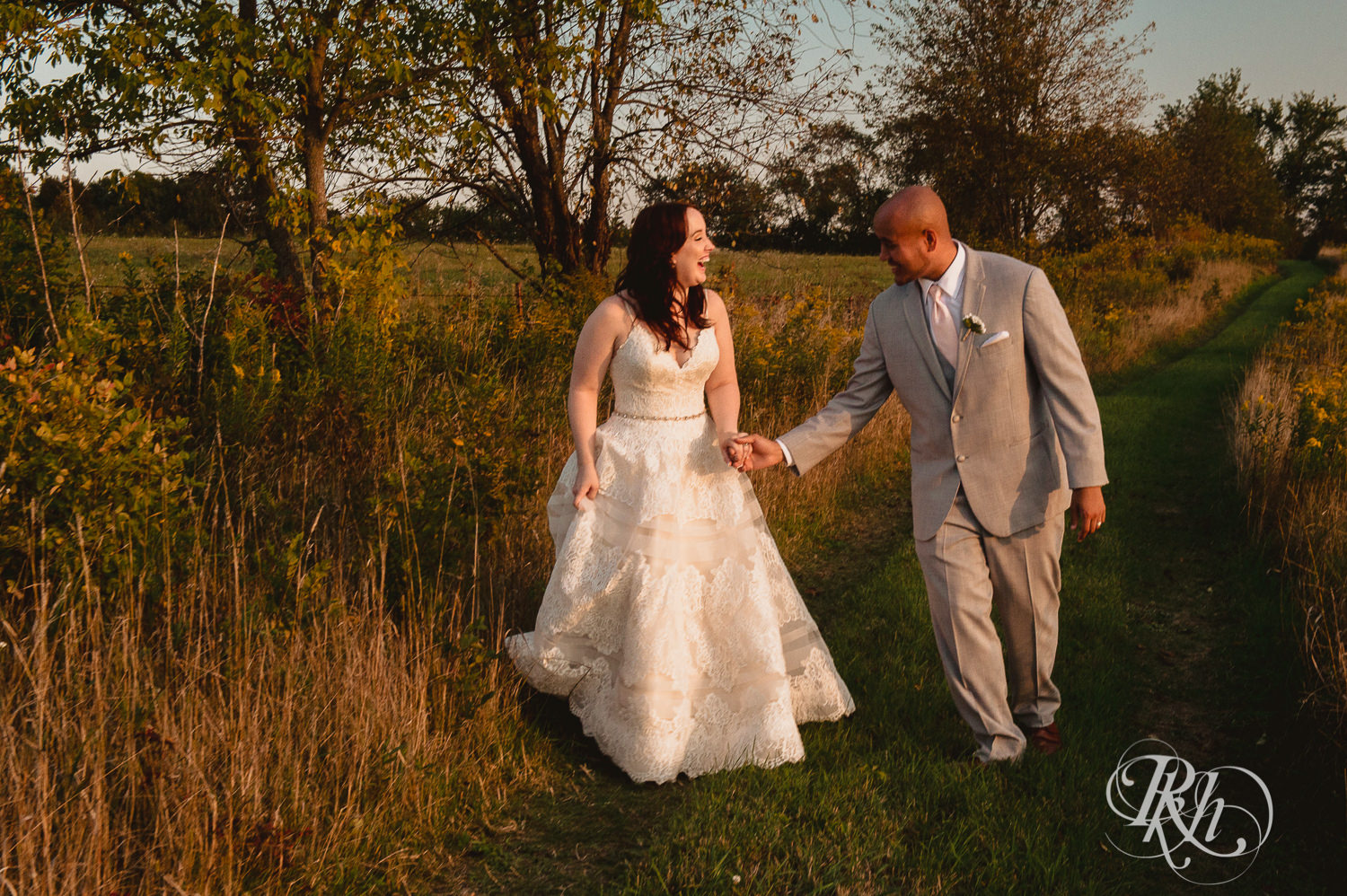 Bride and Asian groom laugh during sunset in field on a hill at Birch Hill Barn in Glenwood City, Wisconsin.