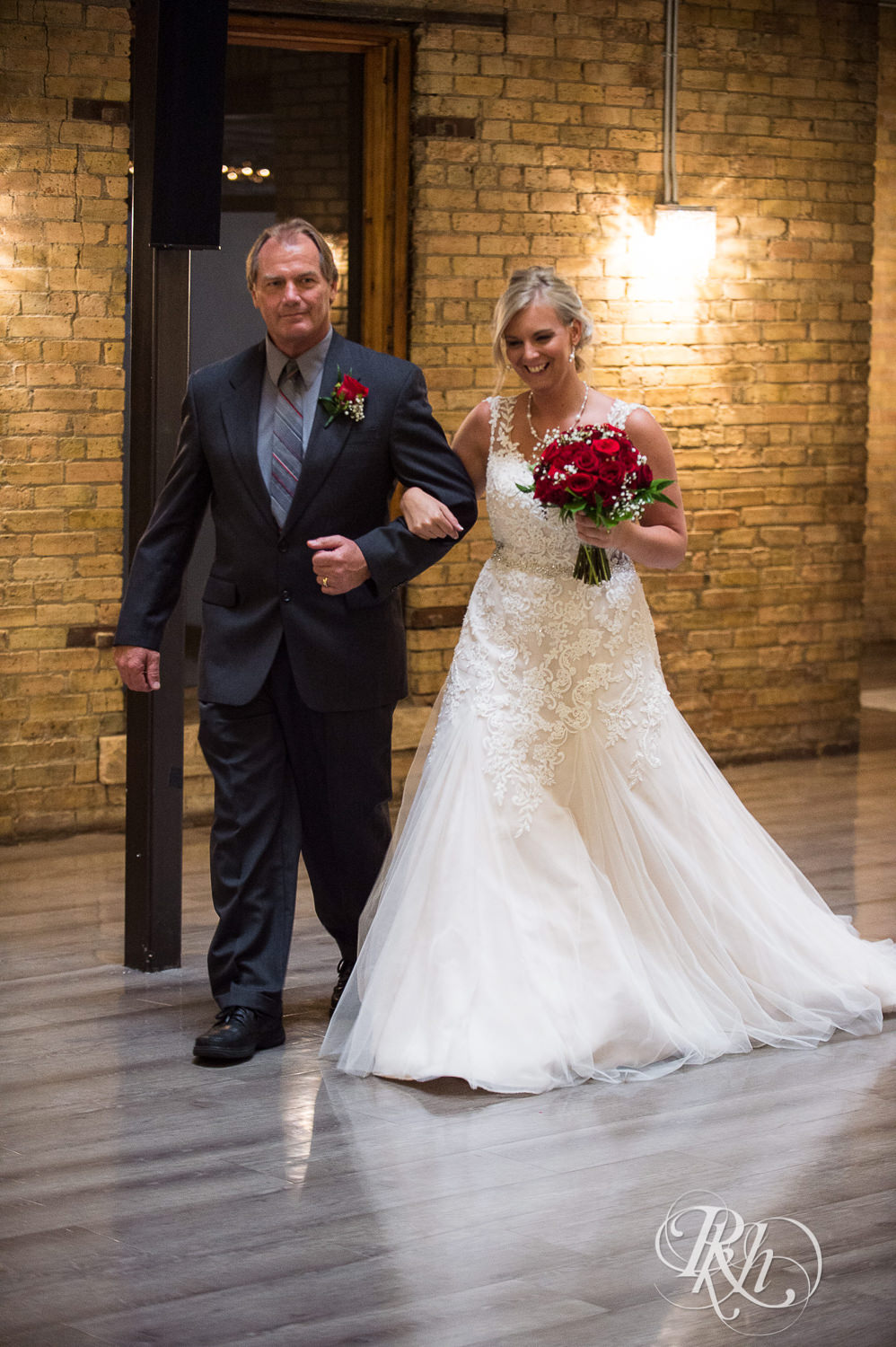 Bride and dad walk down the aisle during wedding ceremony at the Lumber Exchange Event Center in Minneapolis, Minnesota.