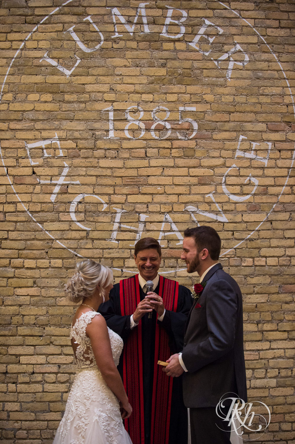 Bride and groom smile during wedding ceremony at the Lumber Exchange Event Center in Minneapolis, Minnesota.