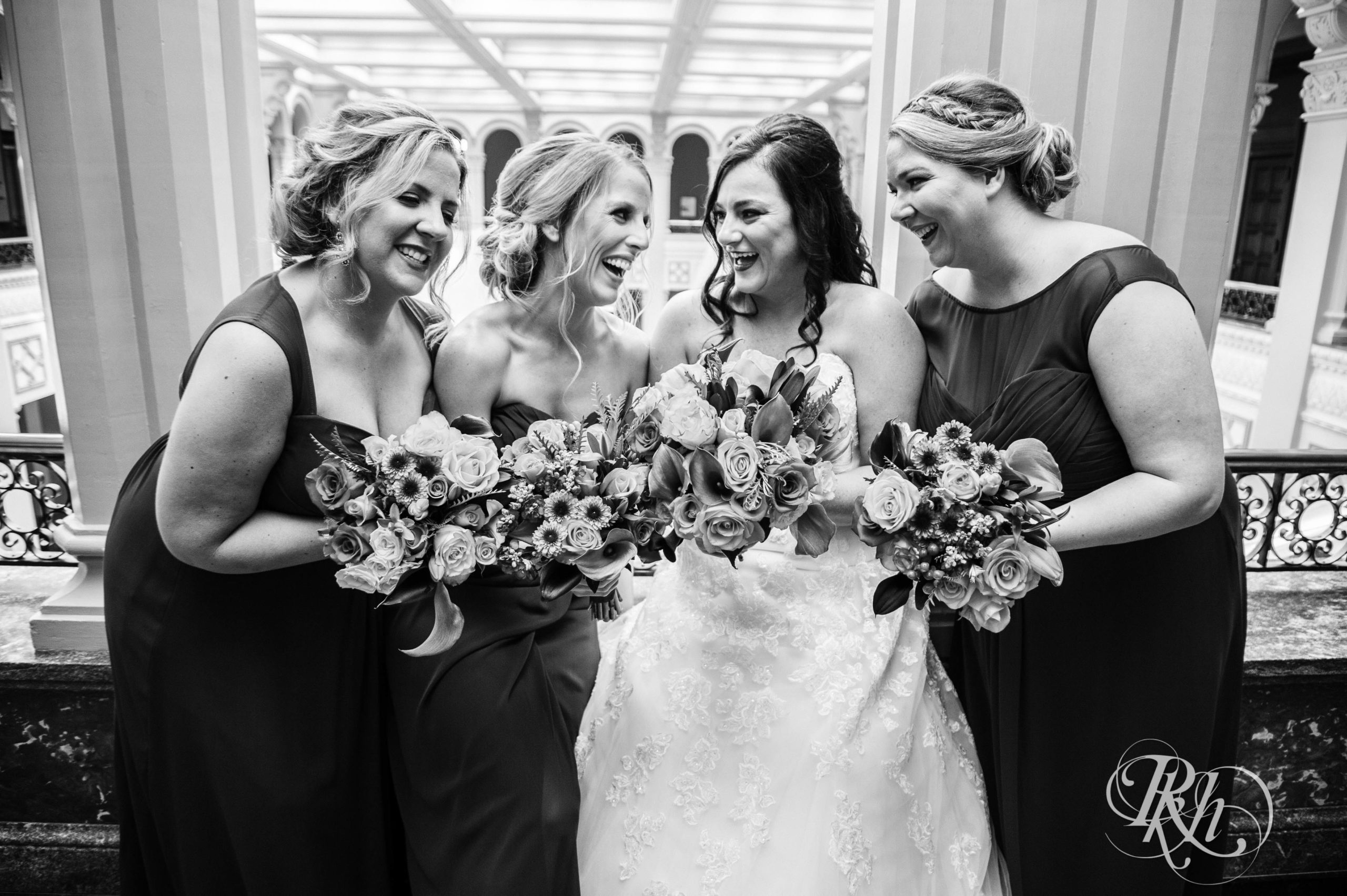 Bride smiles with wedding party at Landmark Center in Saint Paul, Minnesota.