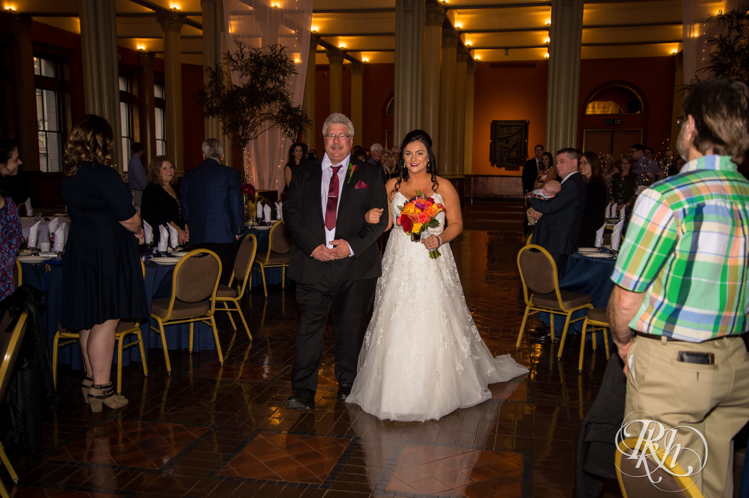 Bride and dad walk down the aisle during wedding ceremony at Landmark Center in Saint Paul, Minnesota.