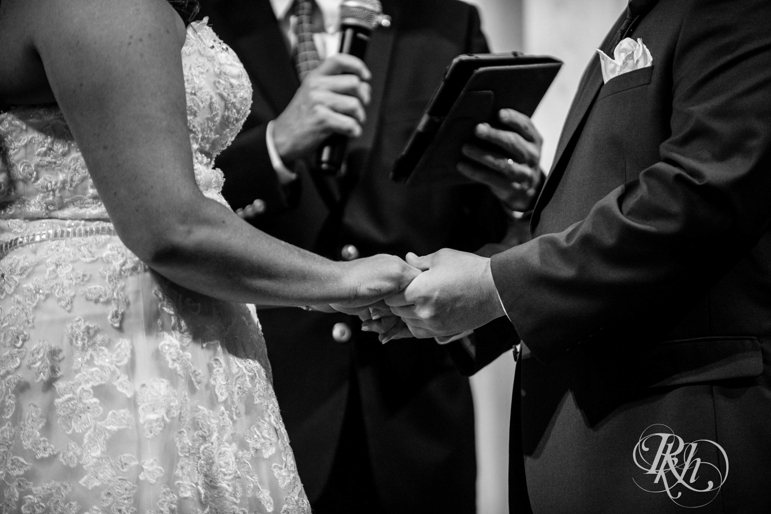 Bride and groom hold hands during wedding ceremony at Landmark Center in Saint Paul, Minnesota.