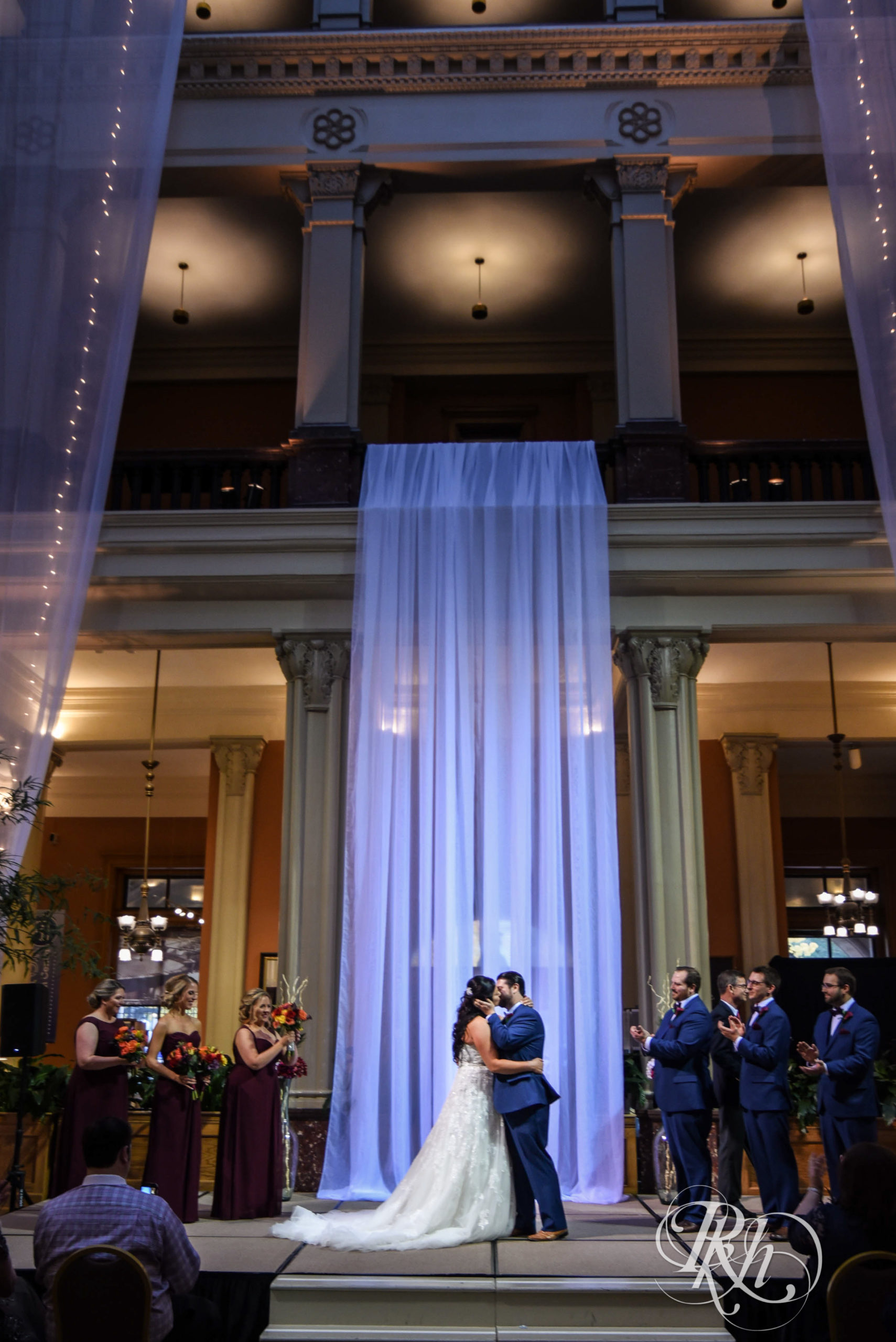 Bride and groom kiss during wedding ceremony at Landmark Center in Saint Paul, Minnesota.