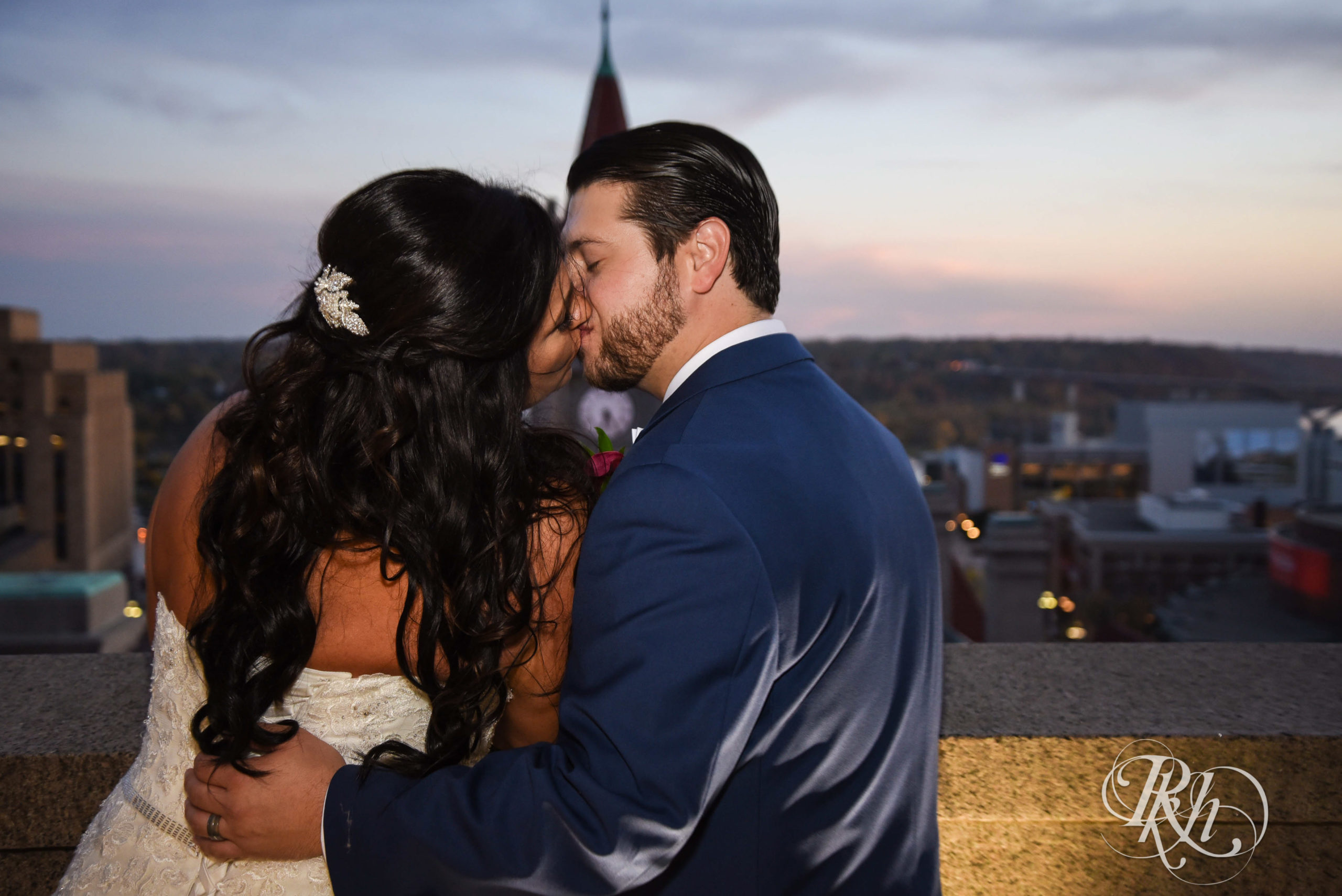 Bride and groom kiss at sunset on wedding day at Landmark Center in Saint Paul, Minnesota.