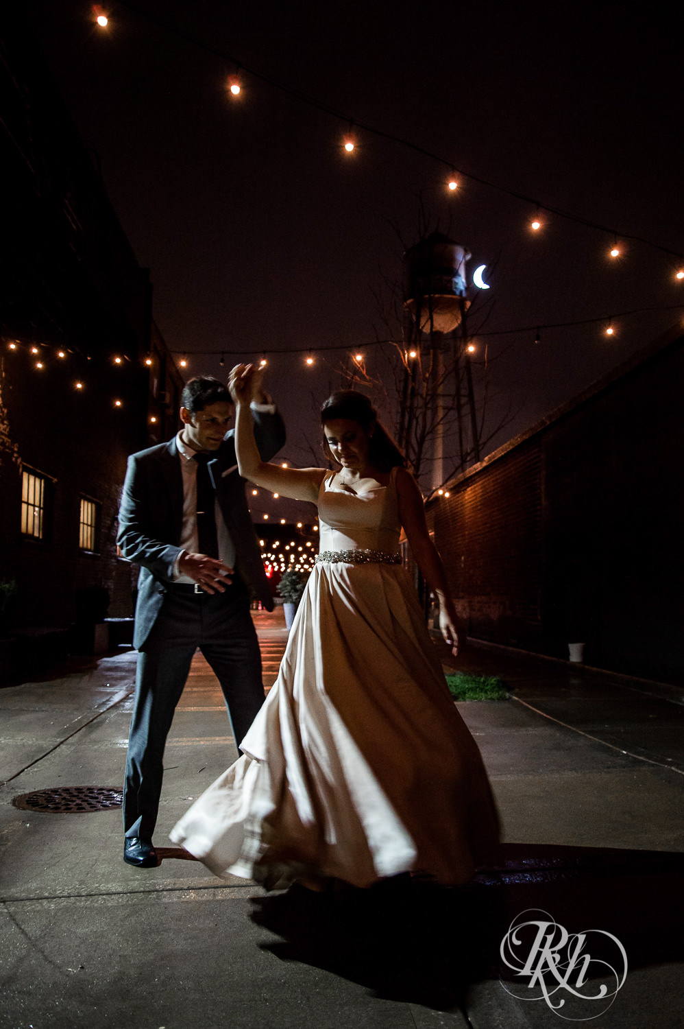Bride and groom dance in the night under cafe lights at Paikka in Saint Paul, Minnesota.