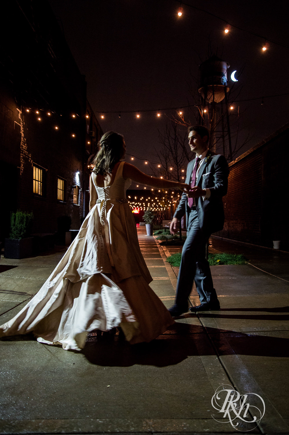 Bride and groom dance in the night under cafe lights at Paikka in Saint Paul, Minnesota.