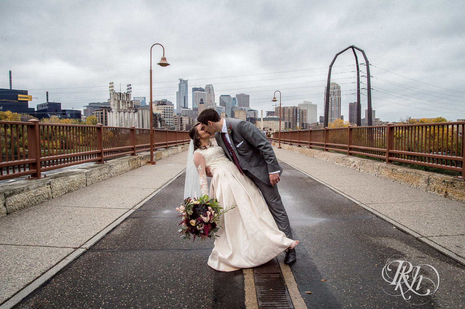 Bride and groom kiss at the Stone Arch Bridge on their rainy wedding day in Minneapolis, Minnesota.