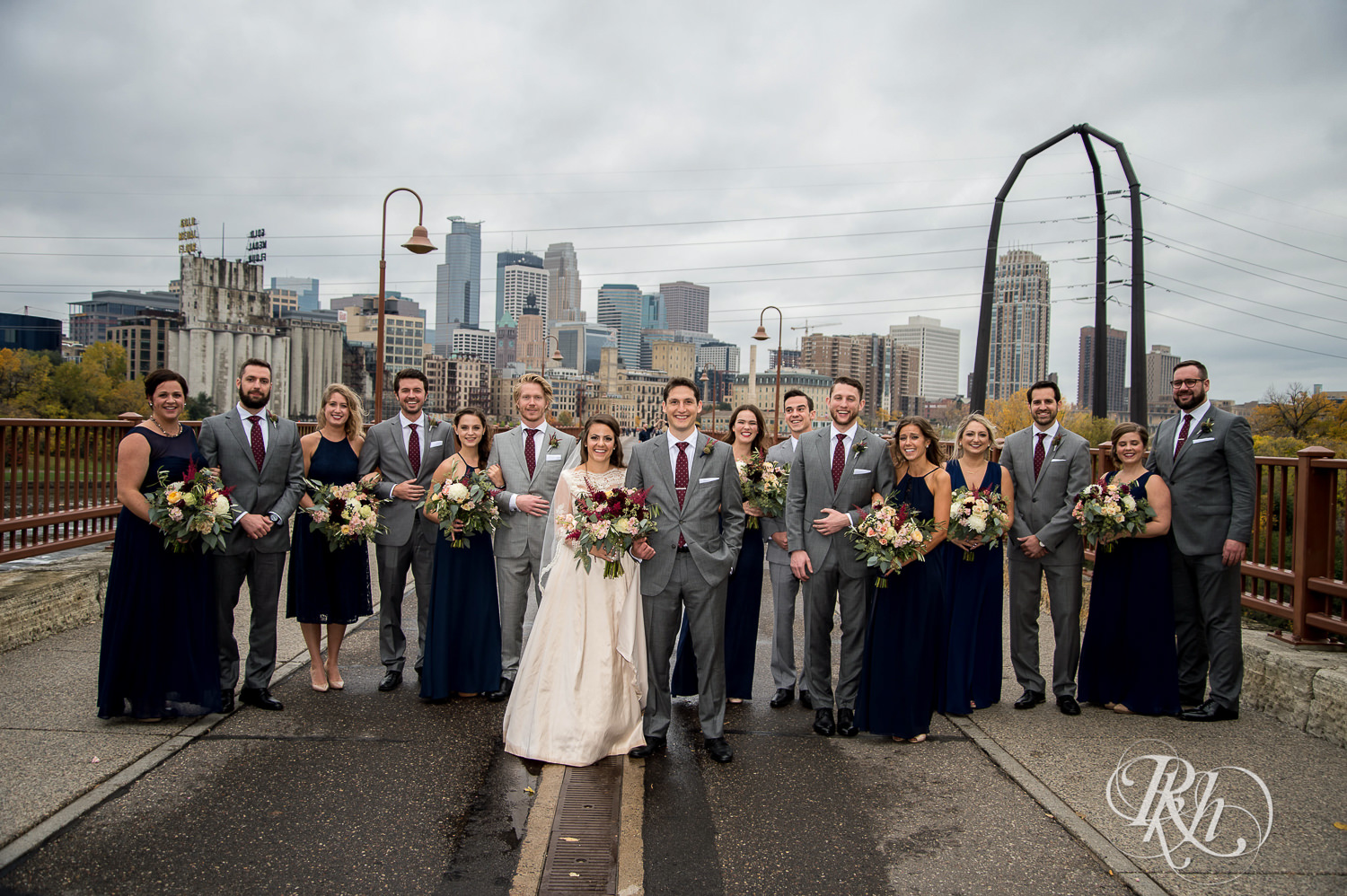 Wedding party smile on the Stone Arch Bridge on a rainy wedding day in Minneapolis, Minnesota.