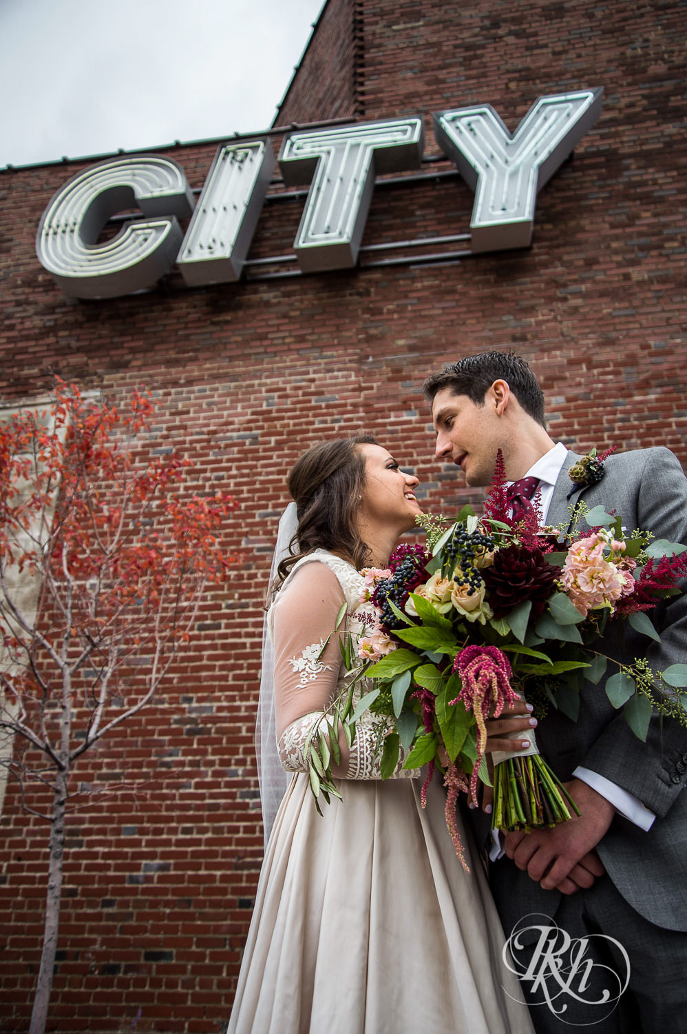 Bride and groom kiss under a City sign on a rainy wedding day in Minneapolis, Minnesota.