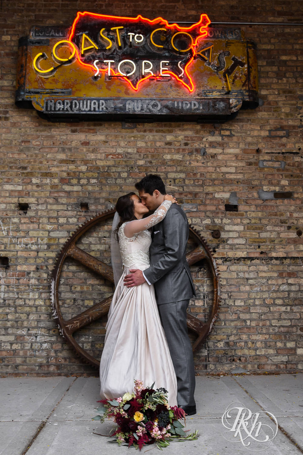 Bride and groom kiss against brick wall on a rainy wedding day in Minneapolis, Minnesota.