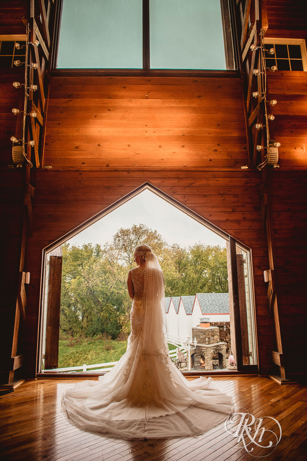 Bride stands in front of large window  at Green Acres Event Center barn wedding in Eden Prairie, Minnesota.