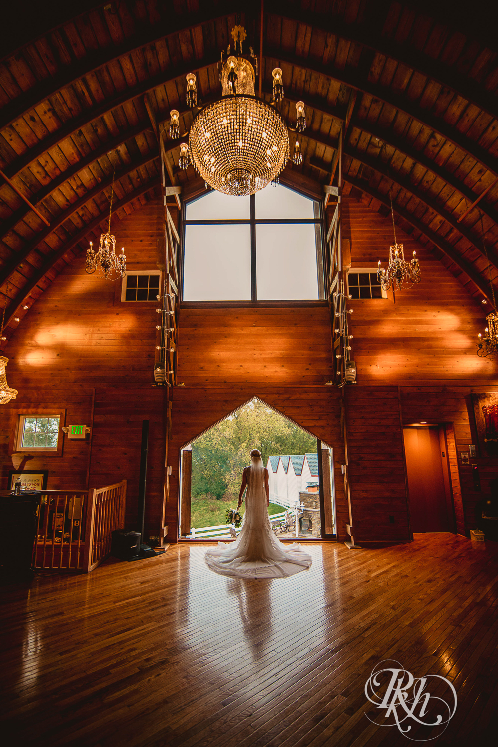 Bride stands in front of large window at Green Acres Event Center barn wedding in Eden Prairie, Minnesota.